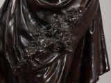 bronze statue of a woman holding a glass of wine in her hand