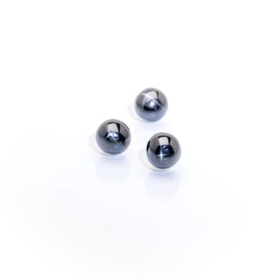 three black glass beads on a white surface with a white background