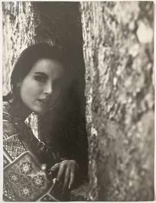 une vieille photo en noir et blanc d'une femme adossée à un arbre