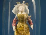 a figurine of a woman in a dress under a glass dome