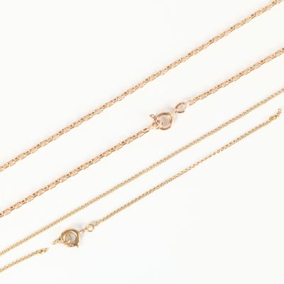 a set of three gold chain necklaces on a white background
