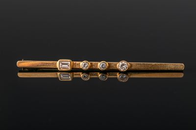 une pince à cravate en or sertie de trois diamants sur un fond noir