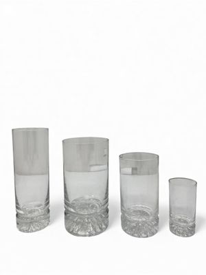 three clear glass vases and one empty glass on a white surface