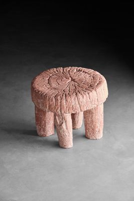 une image représentant un tabouret rose posé sur un sol en béton