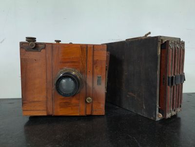 two old wooden cameras sitting on a black table