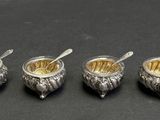 four silverplated bowls with spoons and spoons on a black surface