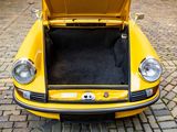 a yellow car with its trunk open on a cobblestone street