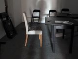 une table et des chaises dans une pièce où se trouve une guitare posée par terre