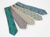 quatre cravates de couleurs différentes sont disposées en rangée sur une surface blanche