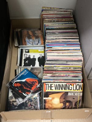 une boîte en carton remplie de CD et des CD par terre