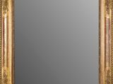un miroir à cadre doré accroché à un mur sur fond blanc