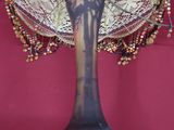 a decorative fan on a stand with beads on it
