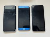 three cell phones are sitting next to each other on a table