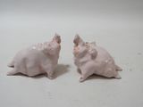 two small pig figurines sitting on a white surface