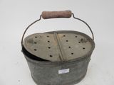 an old metal bucket with a wooden handle on a white surface