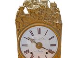 a gold clock with a white face and roman numerals on it