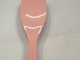 a pink plastic spoon on a table with a white background