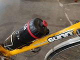 a yellow bicycle with a bottle on the back of it
