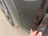 a person holding a measuring tape next to a car