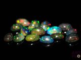 some very pretty colored oplite stones on a black surface