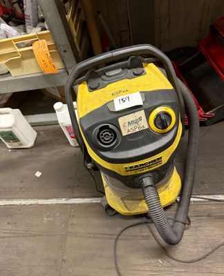 un aspirateur jaune et noir posé par terre dans un garage