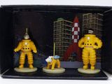 trois figurines d'astronautes dans une boîte, avec une navette spatiale en arrière-plan