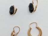three pairs of gold and black earrings on a white surface