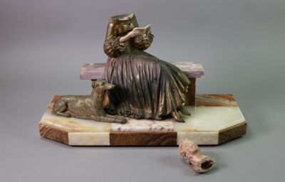 a statue of a woman sitting on a bench reading a book
