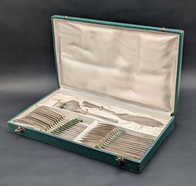 un coffret vert ouvert contenant de l'argenterie, posé sur une surface grise