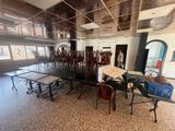 une pièce avec des tables et des chaises, et une femme debout dans l'embrasure de la porte