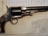 un revolver posé sur un livre dans lequel se trouve un stylo