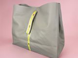 a grey bag with a yellow zipper on the side