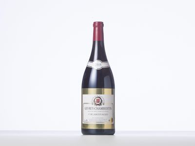 a bottle of red wine sitting on top of a white table