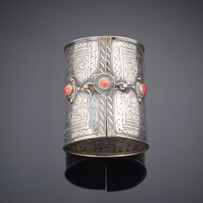 an antique silver bracelet with coral stones on a stand