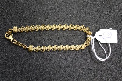a gold chain bracelet with a tag attached to it