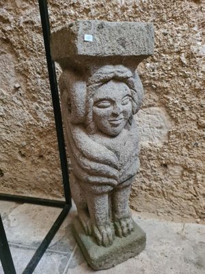 a stone statue of a child holding a bird on its head