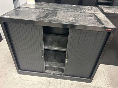 une armoire métallique dont la porte est ouverte et repose sur le sol