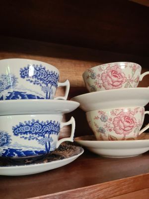 Plusieurs tasses et soucoupes sont posées sur une étagère dans un vaisselier