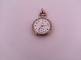 a small gold pocket watch sitting on a white surface