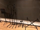 several microphone stands are lined up against a wall in a recording studio