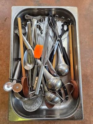 a metal sink filled with various kitchen utensils