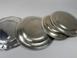 three silver plates with lids are sitting on a white surface