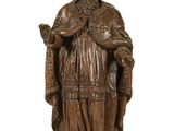 statue en bois représentant un homme coiffé d'un chapeau et vêtu d'une robe, tenant un livre