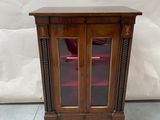 an old wooden cabinet with a glass door and a red chair