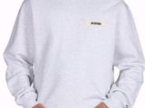 un jeune homme portant un sweat-shirt gris avec un écusson sur la poitrine