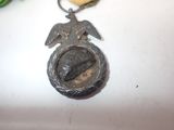 a silver medal with a bird on it next to a flower