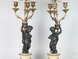 paire de bougeoirs anciens en bronze ornés de chérubins, posés sur des socles en marbre