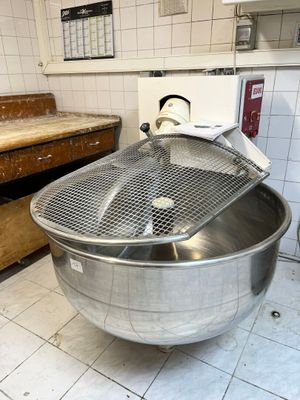 un grand saladier en métal posé par terre dans une cuisine
