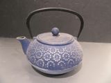 a blue tea pot with a handle on a table