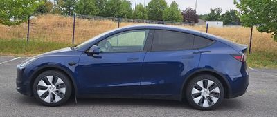 La Tesla Model Y est garée sur un parking près d'un champ.